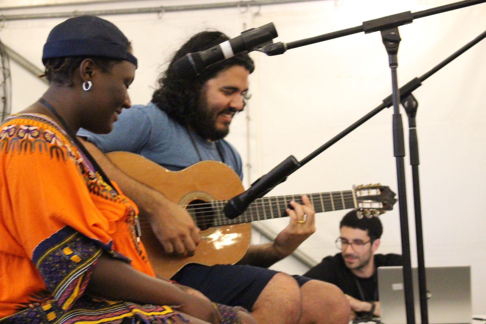 Two youth laughing while playing guitar and singing on stage