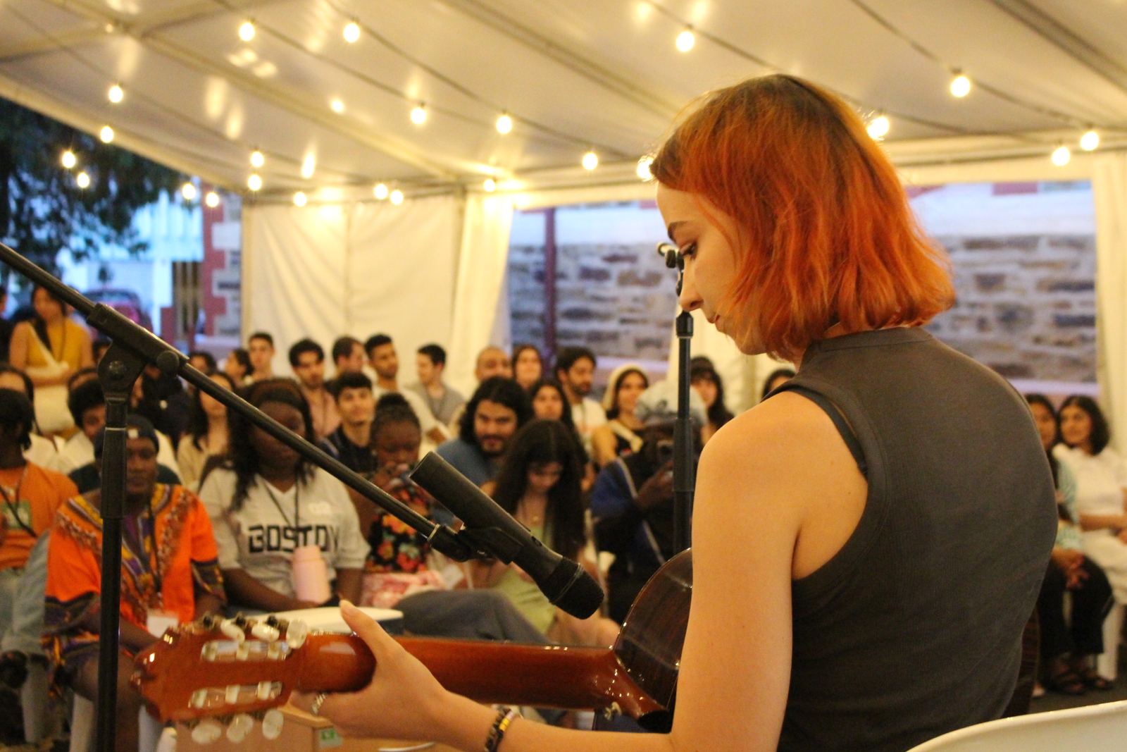 A young woman playing guitar for a full marquee