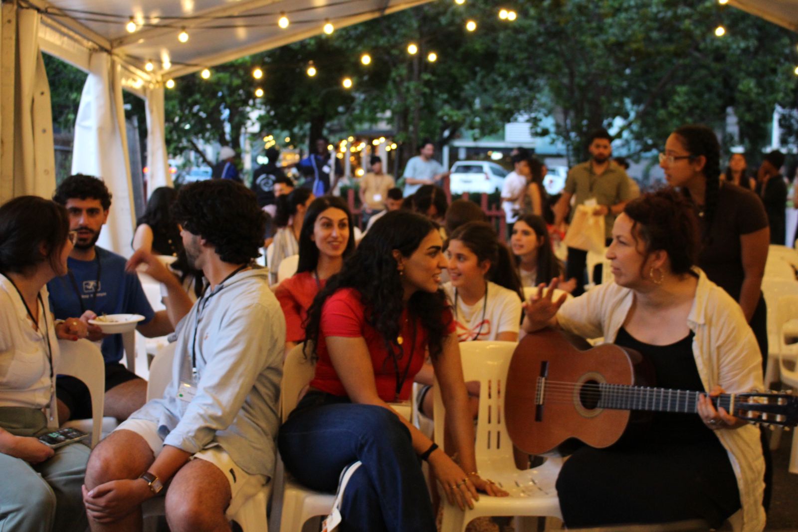 Youth singing together around a guitar in the marquee