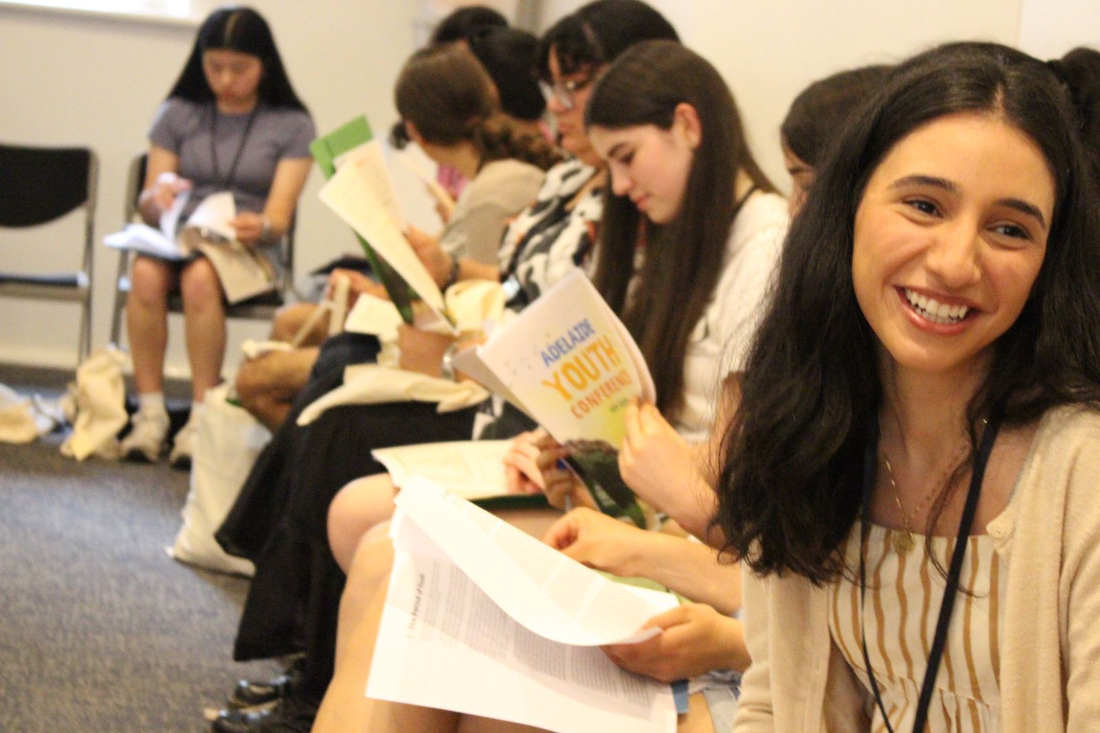 A smiling young woman reading the conference booklet with her group